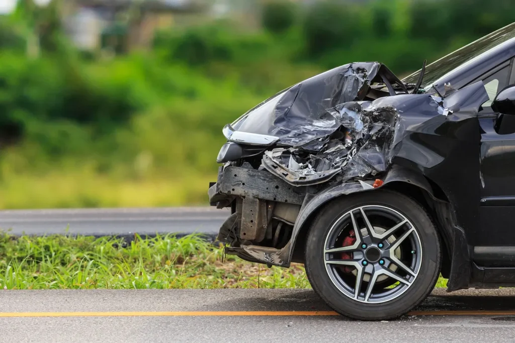 A black car with severe front end damage, after being involved in a car accident.