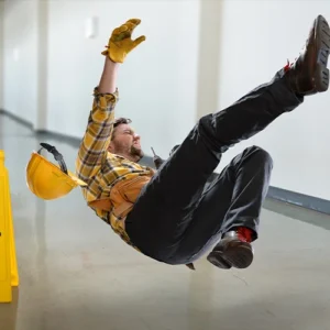 A construction worker, wearing a yellow hardhat falling after slipping.