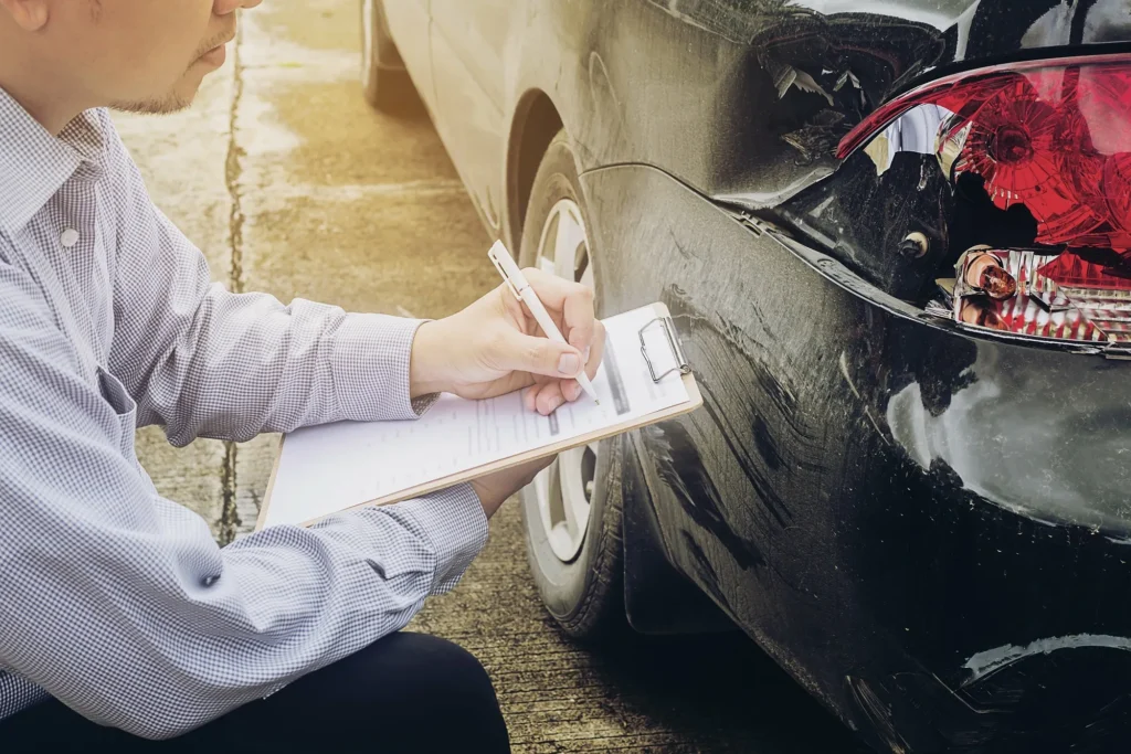 An insurance representative assessing car damage.