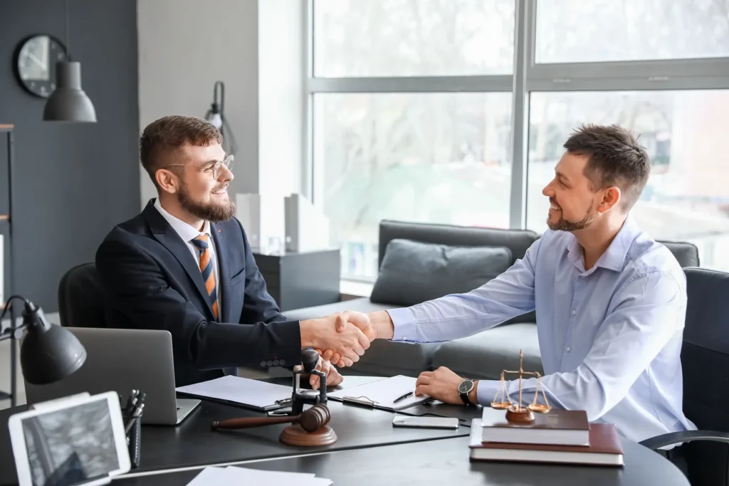 A client shakes hands with a lawyer in an office setting.