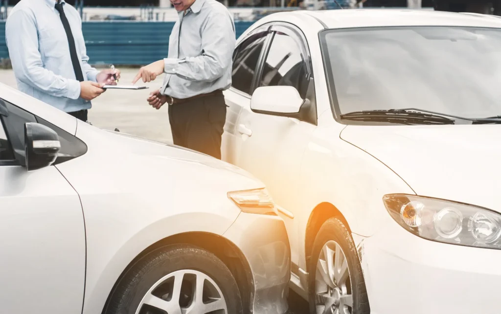 Two cars after an accident with the two drivers exchanging information.