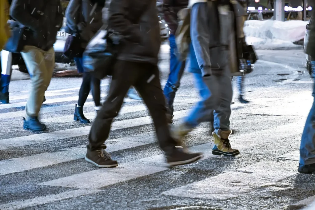 A group of people are crossing the street on a crosswalk.