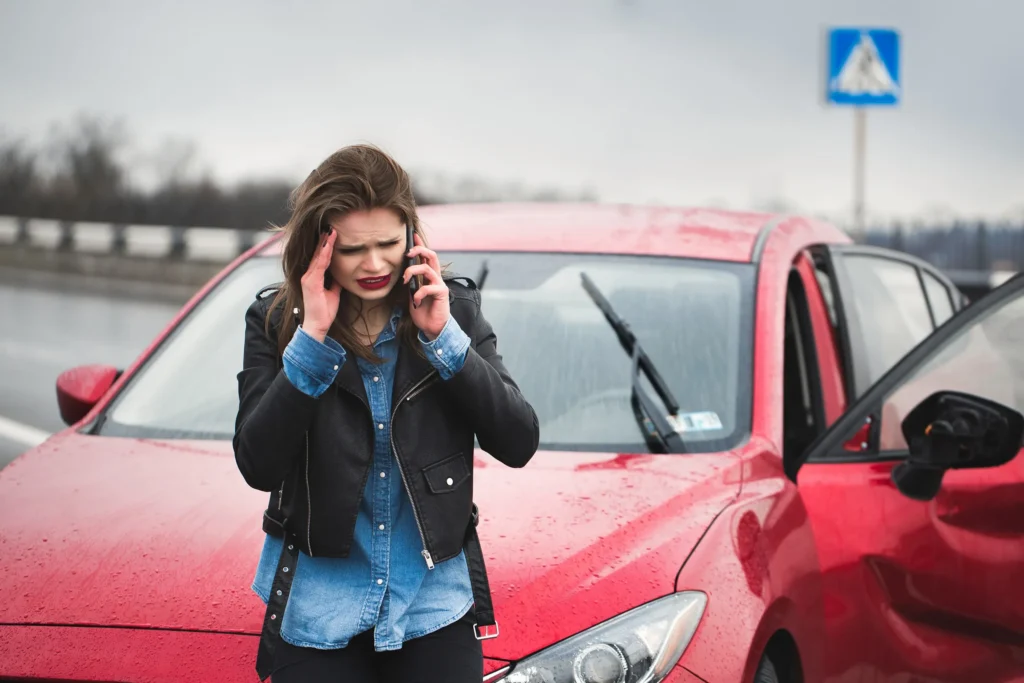 A worried woman on the phone after a car accident in the rain.